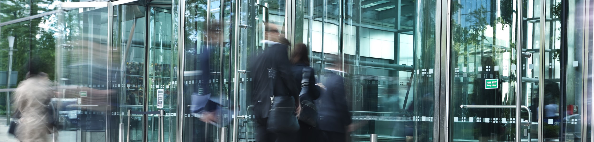 Businesspeople Entering Through Glass Doors of Office Building, Blurred Motion