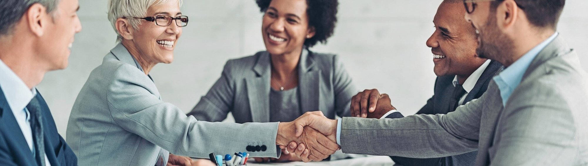 Businesswoman and businessman shaking hands across the table