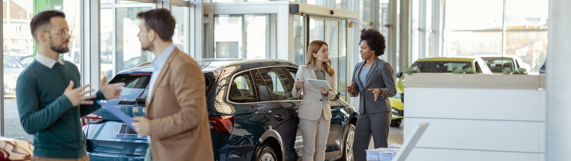 Two sets of people talking in a busy dealership