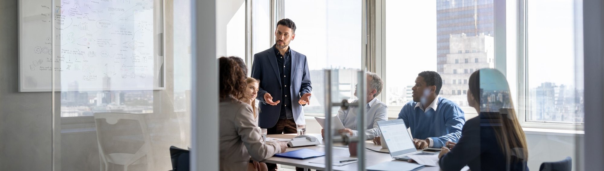 Five professionals in a modern office conference room engaged in a meeting