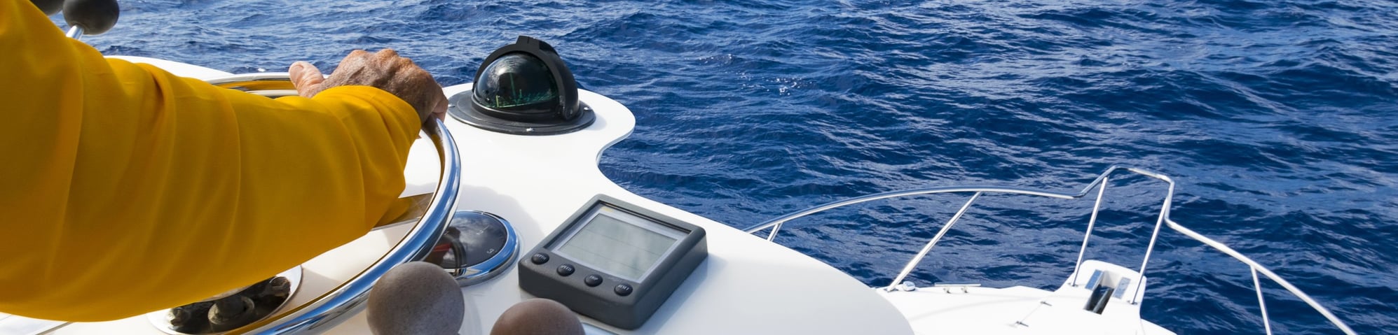 Hand of captain on steering wheel of motor boat in the blue ocean during the fishery day