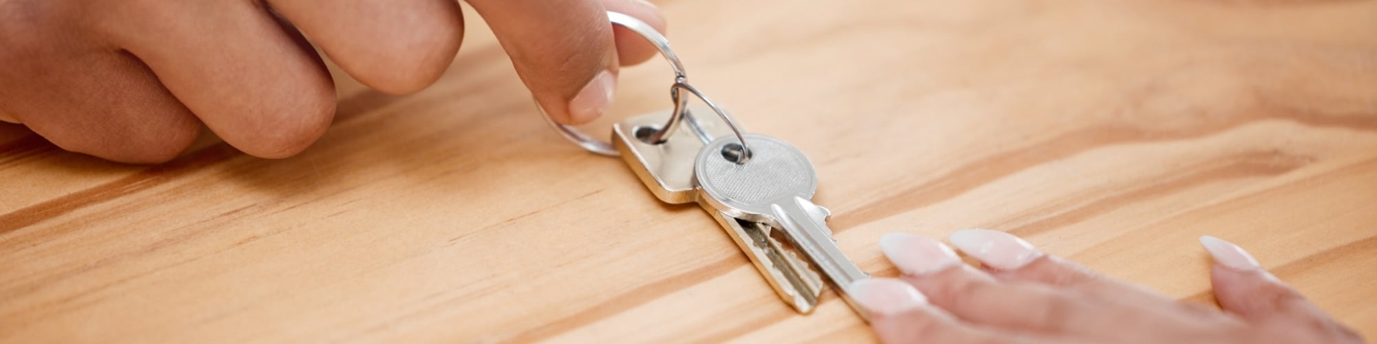 Hands passing keys across a table
