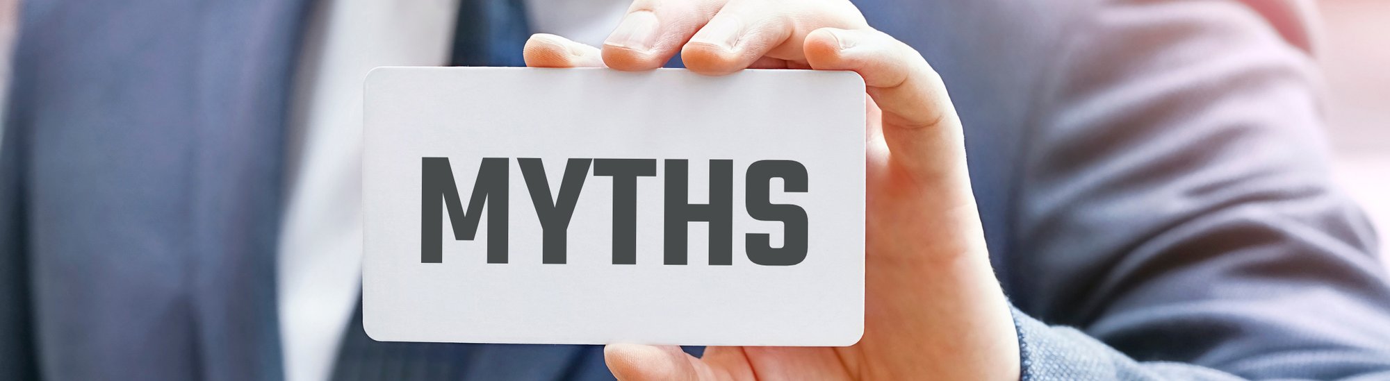 Businessman in blue suit holding up access card with "MYTHS" written on it