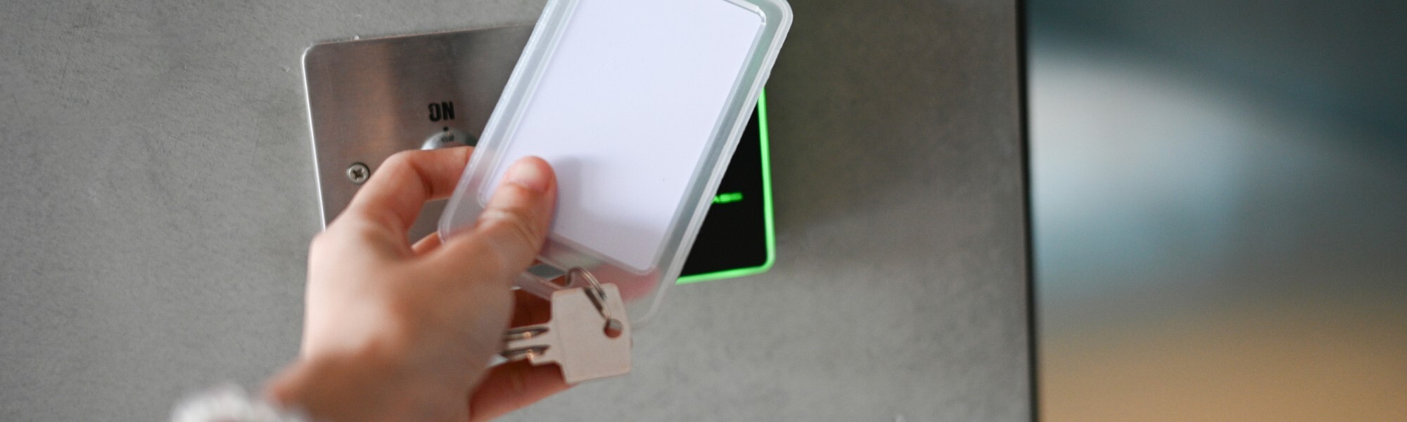 Person presenting an access card to an electronic door reader while holding a physical key