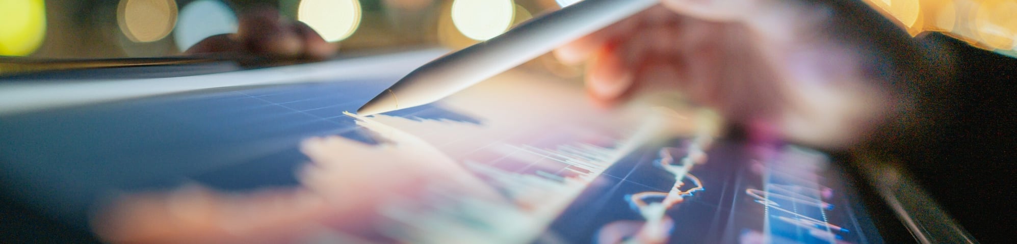 Person using stylus on tablet with blurred city scene in background