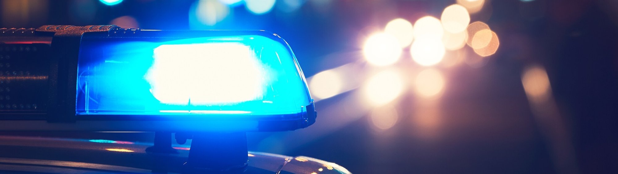 Blue police light in the foreground with blurred city lights in the background Blue police light in the foreground with blurred city lights in the background