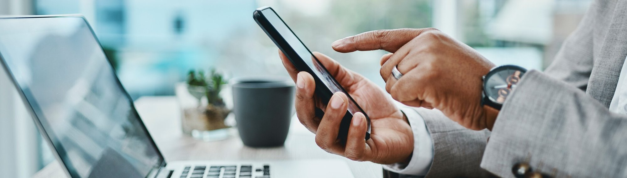 Shot of a businessman using a smartphone and laptop in a modern office